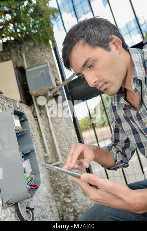 Elettricista guardando una vecchia scatola fusibili Foto Stock