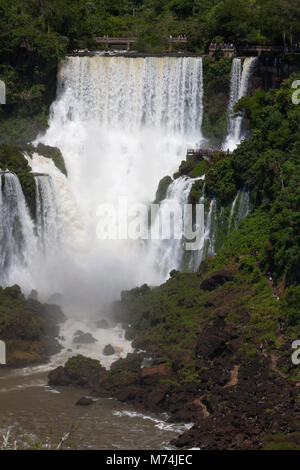 Panorama elevata Iguazu Falls cascate con prospettiva lontana piccoli turisti sul marciapiede sentiero UNESCO World Heritage Site meraviglie naturali del mondo Foto Stock