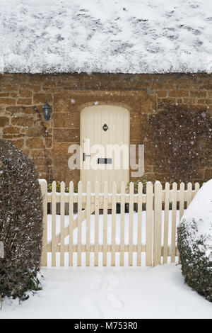 Con il tetto di paglia cottage in pietra in inverno la neve. Grande Tew, Cotswolds, Oxfordshire, Inghilterra Foto Stock