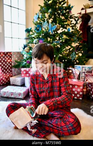 Ragazzi di età compresa tra 10-14 sulla mattina di Natale accanto all'albero di Natale con presenta Foto Stock