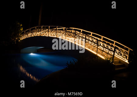 Una lunga esposizione di un illuminato ponte piede su una piscina di notte. Foto Stock