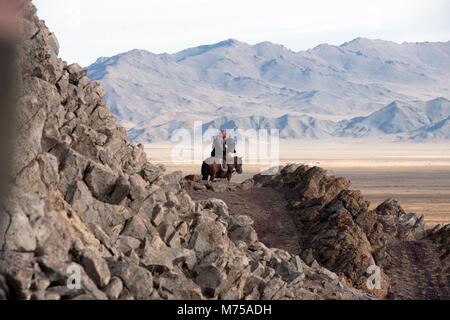 Un nomade kazako a cavallo a caccia con il suo golden eagle nelle montagne di Altai della Mongolia occidentale. Foto Stock