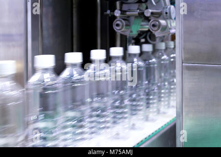 Trasparente di bottiglie di plastica sul nastro trasportatore in movimento molto rapido di acqua nella macchina di riempimento nell'acqua potabile fabbrica. industria delle bevande. Foto Stock