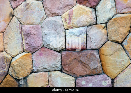 Muro di pietra è costruita dalla bella multi colore pietre naturali con diverse dimensioni delle rocce. Sfondo e sfondo. Foto Stock