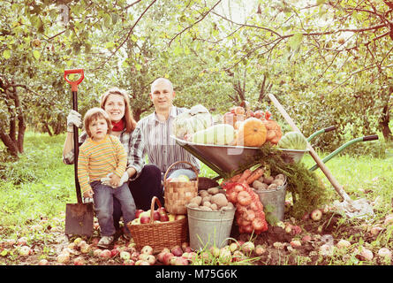 Felici i genitori e il bambino con ortaggi raccolti in giardino Foto Stock