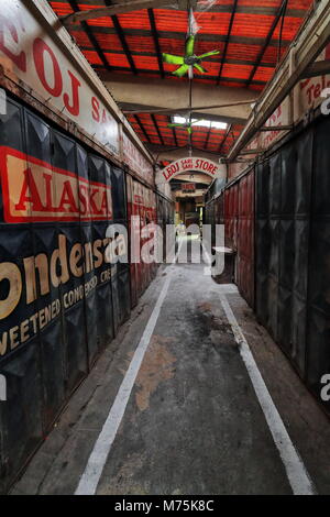 Bacolod, Philippines-October 12, 2016: Corridoio chiuso tra le bancarelle del mercato mostra la pubblicità di prodotti locali sul ferro porte pieghevoli di t Foto Stock