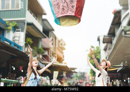 Felice due ragazza rilasciare lasciar andare il cielo lanterne all'aria. Traduzione su sky lanterns testo 'speranze di felicità e buona fortuna in amore la vita del futuro". Foto Stock