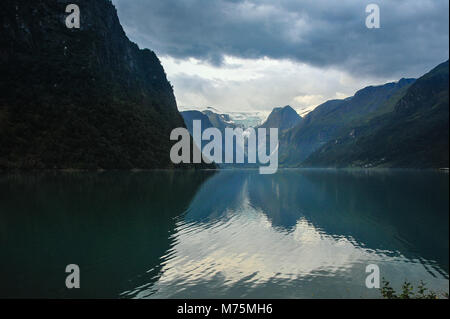 Lago Oldevatnet nella valle Oldedalen, Norvegia. In lontananza il Ghiacciaio Briksdal, grigio stormclouds e riflessione di montagna Foto Stock