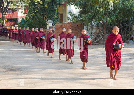 Processione di monaci buddisti che raccolgono elemosine a Bagan, Myanmar (Birmania), Asia in febbraio Foto Stock