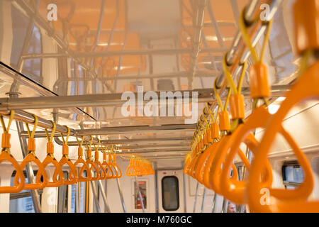 Maniglie di colore arancione per il passeggero in piedi all'interno di un metro Foto Stock