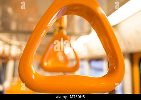 Maniglie di colore arancione per il passeggero in piedi all'interno di un metro Foto Stock