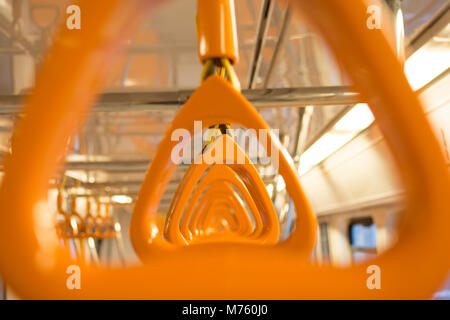 Maniglie di colore arancione per il passeggero in piedi all'interno di un metro Foto Stock