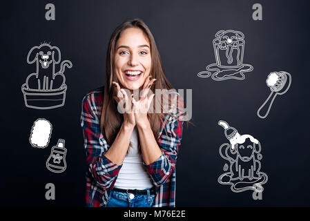Positivo donna sorridente mentre vedendo un grazioso piccolo cucciolo Foto Stock