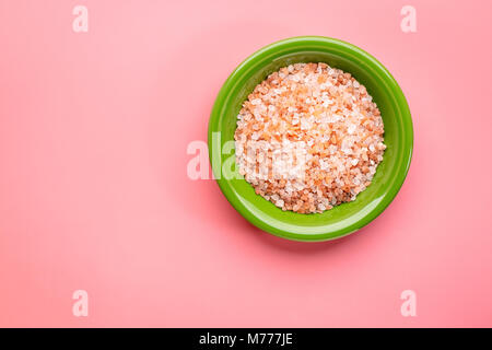 Cristalli grossolani di rosa Sale Himalayano nel recipiente di ceramica su uno sfondo rosa, vista dall'alto con una copia spazio Foto Stock