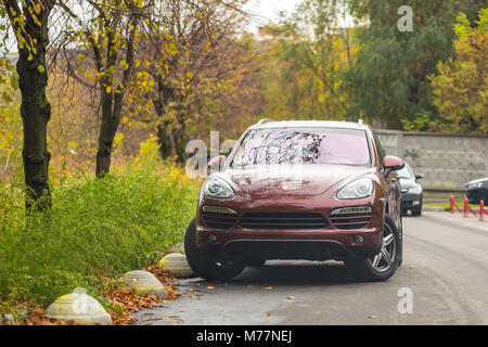 Kiev, Ucraina - 17 Ottobre 2017: Brown Porsche Cayenne parcheggiato all'aperto sotto gli alberi Foto Stock