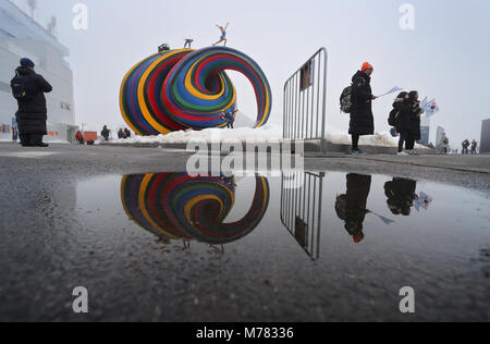 08 marzo 2018, Corea del Sud, PyeongChang: Paralimpiadi, cerimonia di apertura: una scultura e un gruppo di visitatori si riflettono in una pozzanghera fuori dallo stadio. Foto: Karl-Josef Hildenbrand/dpa Foto Stock