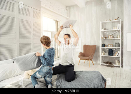 Felice papà e figlio avente un cuscino lotta Foto Stock