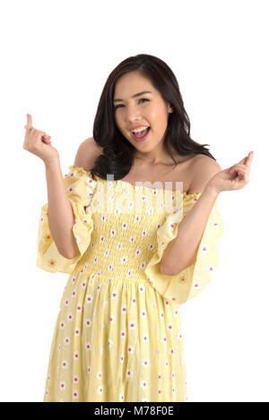 Carino ragazza asiatica che indossa giallo abito floreale per la primavera o estate in posa mini cuore in studio su sfondo bianco. Foto Stock