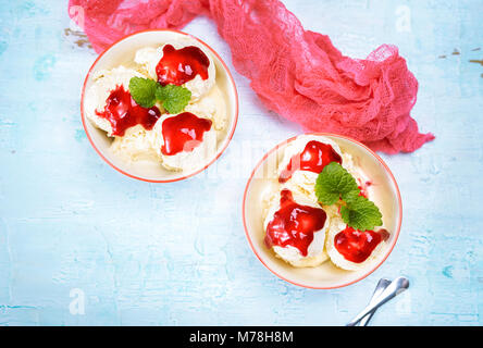 Vista superiore del delizioso gelato alla vaniglia sfere in due ciotole versata con salsa alle ciliegie. Spazio di copia Foto Stock