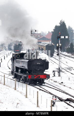 Severn Valley Railway Locomotiva 7714 sbuffando lungo coperto di neve e piste, uscire dalla stazione a Kidderminster su un terribilmente freddo mattino marzo, 2018. Foto Stock