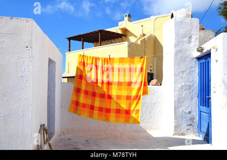 Il Pyrgos, Santorini / Grecia - Marzo 7, 2011: un arancio e giallo copriletto, appesi ad asciugare su un tetto nel villaggio di Pyrgos, Santorini, Grecia Foto Stock