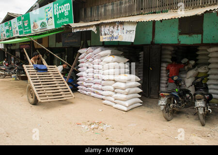 Un fornitore a Nyaung U la vendita sul mercato dei sacchi di riso o farina. Uomo birmano con improvvisati carrello in legno con pneumatici e ruote. Bagan, MYANMAR Birmania Foto Stock