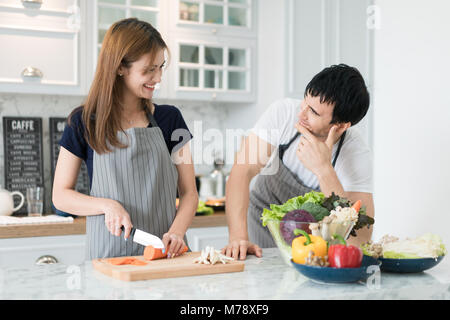 Giovani asiatici giovane preparare il cibo insieme al contatore in cucina. Felice amore giovane concetto. Foto Stock