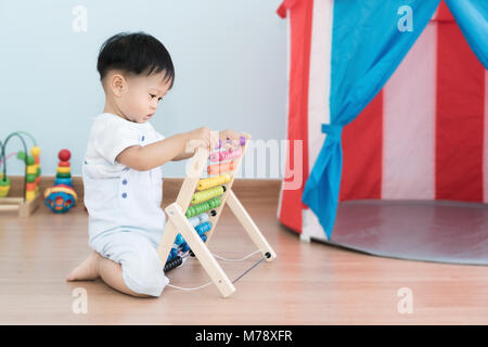 Asian bimbo impara a contare. Carino bambino che gioca con abacus giocattolo. Little Boy divertirsi al chiuso in casa. Il concetto educativo per il bambino. Foto Stock