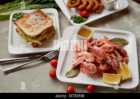 Snack di birra al pub o bar.Gamberetti, gustosi sandwich e Golden anelli di cipolla. Foto Stock