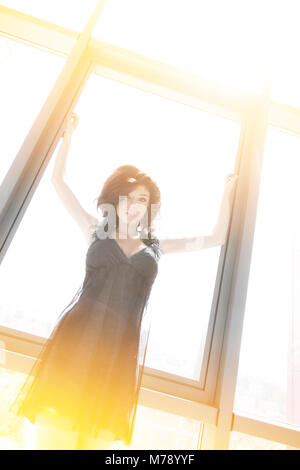 Giovane bella donna si allunga le braccia sulla finestra Foto Stock