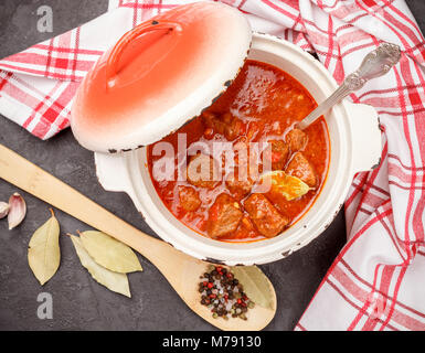 Il gulasch è un tradizionale piatto ungherese di stufato di manzo con verdure in una spessa salsa di pomodoro con spezie in ghisa pentola. Messa a fuoco selettiva Foto Stock