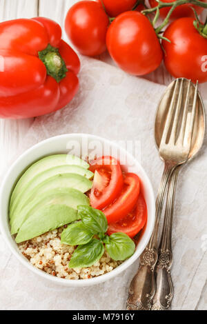 Quinoa calda con insalata di verdure - avocado, cipolla rossa, pomodori, peperone, basilico e olio di oliva. Granella sano, super duper. Messa a fuoco selettiva Foto Stock