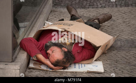 La persona senza dimora che dorme sul percorso in una scatola di cartone Foto Stock