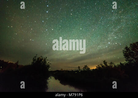 Stelle e il cielo notturno su un piccolo lago con alberi con le lucciole Foto Stock