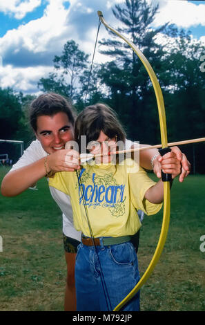 Una giovane ragazza riceve una lezione di sport del tiro con l'arco dal suo consigliere presso un campo estivo in Vermont, Stati Uniti, Nord America. Foto Stock