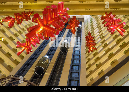 Ascensori di vetro rosso e decorazioni per il nuovo anno cinese nell atrio della Pan Pacific Marina Bay Hotel, Singapore. Foto Stock