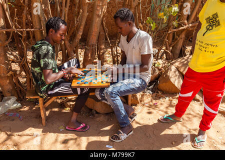 Due giovani uomini giocano le bozze (DAMA) utilizzando tappi di bottiglie, Dimeka, Valle dell'Omo, Etiopia Foto Stock