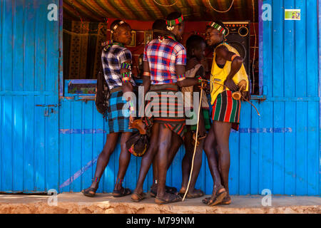 Giovani Hamar uomini al di fuori di un telefono cellulare (telefono cellulare) negozio durante la loro visita settimanale al mercato tribale In Dimeka, Valle dell'Omo, Etiopia Foto Stock