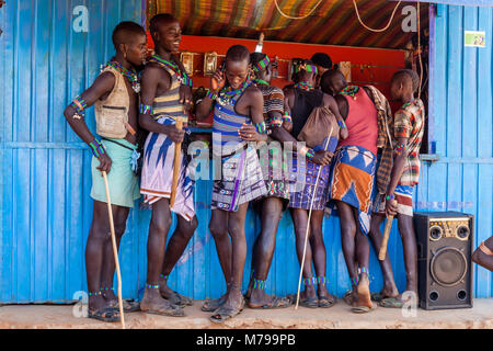 Giovani Hamar uomini al di fuori di un telefono cellulare (telefono cellulare) negozio durante la loro visita settimanale al mercato tribale In Dimeka, Valle dell'Omo, Etiopia Foto Stock