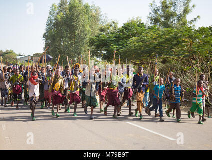 Oromo uomini e ragazzi con bastoni, bastoni e armi ballare e festeggiare felicemente un matrimonio, Regione di Oromo, Sambate, Etiopia Foto Stock
