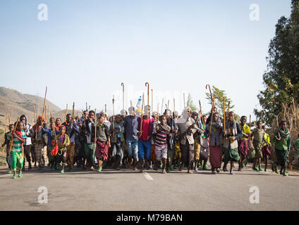 Oromo uomini e ragazzi con bastoni, bastoni e armi ballare e festeggiare felicemente un matrimonio, Regione di Oromo, Sambate, Etiopia Foto Stock