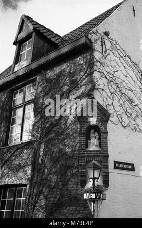 Peerdenstraat: una vecchia casa da sopra il ponte sul canale Groenerei in fondo Peerdenstraat, Brugge, Belgio: una Madonna e Bambino in una nicchia di mattoni. Film in bianco e nero fotografia Foto Stock