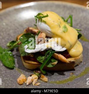 Salmone e Uovo affogato servita con verdure di stagione e tappoed con salsa olandese. Il piatto viene servito su toast a lievitazione naturale. Foto Stock