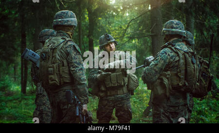 Leader di squadra militare discute i dettagli di funzionamento con i soldati, comandante dà gli ordini. Completamente attrezzato e soldati armati pronto per la missione nella foresta Foto Stock