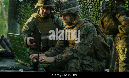 Militare Base di staging, funzionario dà gli ordini al Chief Engineer, essi utilizzare la radio e il grado dell'esercito, portatile. Essi sono in mimetizzata tenda in una foresta. Foto Stock