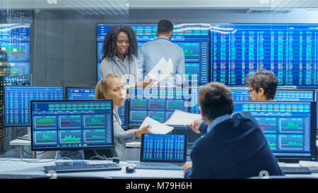 Multi-Ethnic team di operatori è occupato a lavorare presso la borsa in ufficio. I concessionari e i broker di acquistare e vendere le scorte sul mercato. Foto Stock