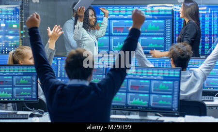 Multi-Ethnic team di operatori hanno giornata di successo presso la borsa in ufficio. I concessionari e i broker festeggiare il successo. Foto Stock
