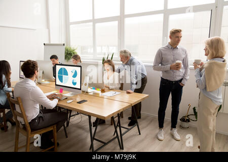 Giovani e dipendenti senior facendo diverse attività di ufficio in Foto Stock