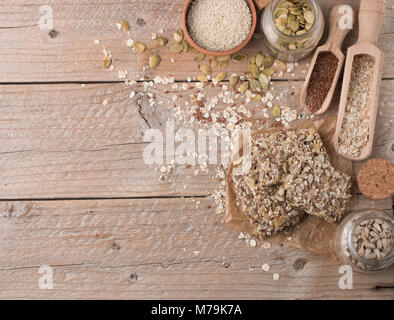 Snack sani - Croccante cereale cookie sul vecchio tavolo in legno e ingredienti: fiocchi d'avena, semi di lino, zucca, semi di girasole, di sesamo. Dieta cracker croccanti. Co Foto Stock