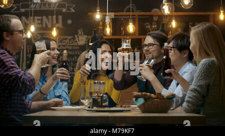 Diversi gruppi di amici festeggiare con un brindisi e il Clink sollevato bicchieri con bevande varie nella celebrazione. Bella Giovani Divertirsi Foto Stock